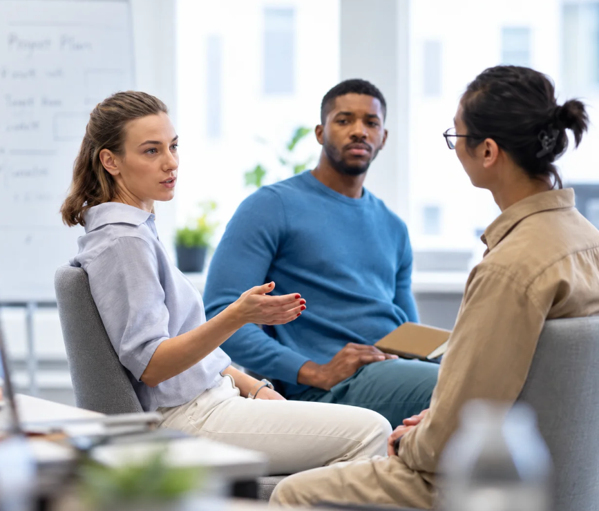 Three adults in conversation in a bright office
